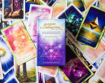 May include: A purple and gold box with the text "Akashic Illumination Deck" and "Awaken, Activate, and Accelerate your Akashic Records Experience!"  The box is surrounded by a variety of colorful cards with images and text, including "Dreams", "Symbols", "Infusions", "Life Path", and "Explorations".