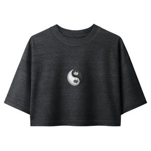 May include: A charcoal gray cropped t-shirt with short sleeves and a crew neckline. Centered on the chest is a circular yin-yang symbol in black and white. The word inhale is printed in black on the white half, and exhale is in white on the black half.