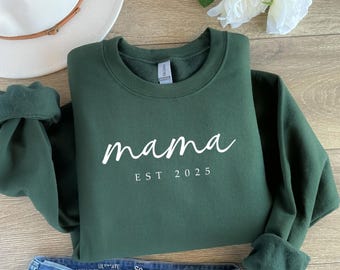 May include: A dark green sweatshirt with the text "mama est 2025" in white.