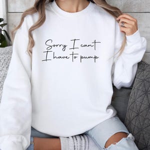Può includere: Felpa bianca con la scritta nera "Sorry I can't I have to pump". La felpa è a girocollo e sembra essere realizzata in un materiale morbido. L'immagine mostra la felpa indossata.