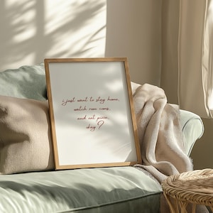May include: A framed print with a white background and a red handwritten quote that reads: "i just want to stay home, watch rom coms, and eat pizza, okay?"