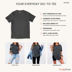 K&ouml;nnte beinhalten: Dunkelgraues Unisex-T-Shirt mit dem Text "YOUR EVERYDAY GO-TO TEE" und Produktdetails. Das Shirt wird in figurbetonten, lockeren und &uuml;bergro&szlig;en Stilen gezeigt. Merkmale sind 100 % Ringspun-Baumwolle, ein gef&auml;rbtes Finish und ein weiches Tragegef&uuml;hl.