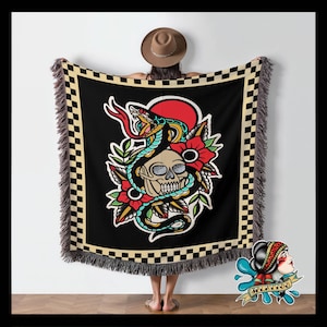 May include: A black and white checkered throw blanket with a fringed edge features a colorful illustration of a snake wrapped around a skull with red and green flowers. The illustration is in a traditional tattoo style.