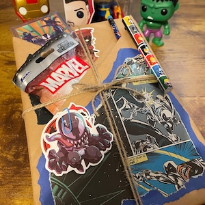 May include: A brown paper package wrapped with twine and decorated with Marvel comic book characters, stickers, and a small bag labeled "Marvel".