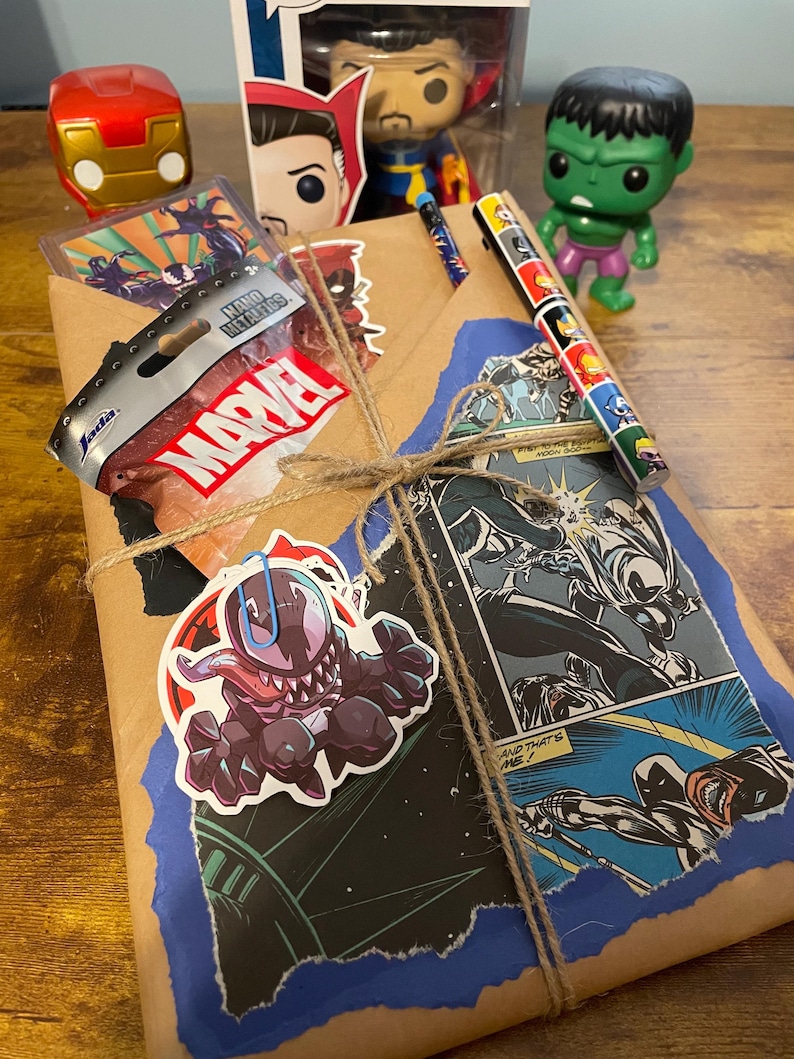 May include: A brown paper package wrapped with twine and decorated with Marvel comic book characters, stickers, and a small bag labeled "Marvel".