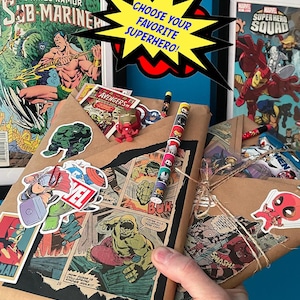 May include: A brown paper gift bag wrapped with comic book pages featuring superheroes like Hulk and Sub-Mariner. The bag is decorated with stickers of various superheroes, including Deadpool, Thor, and Captain America. The bag is tied with twine and has a tag that says "Choose your favorite superhero!"
