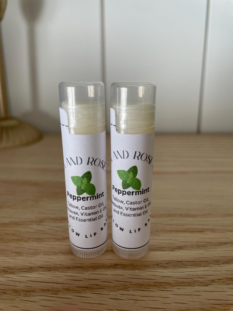 May include: Two white tubes of peppermint lip balm with green leaf designs and the text "Peppermint" and "Tallow, Castor Oil, Beeswax, Vitamin E Oil and Essential Oil" on the labels.