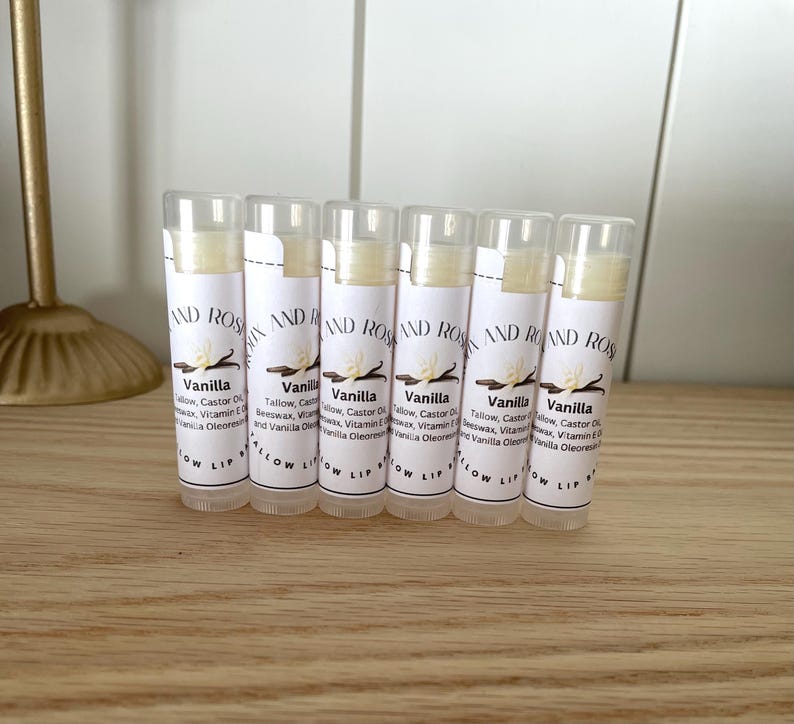 May include: Six white tubes of lip balm with a white label that says "Vanilla" and lists the ingredients. The label also says "Glow Lip" at the bottom.