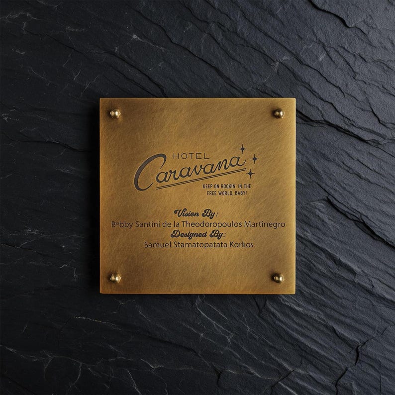 May include: A square brass plaque with four corner studs featuring the engraved text Hotel Caravana, Keep on Rockin in the Free World, Baby, Vision By: Bobby Santini de la Theodoropoulos Martinegro, and Designed By: Samuel Stamatopatata Korkos.