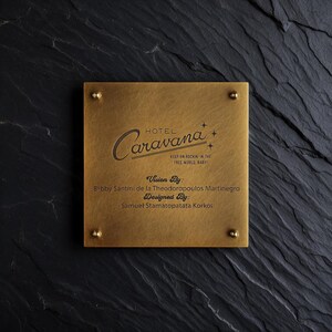 May include: A square brass plaque with four corner studs featuring the engraved text Hotel Caravana, Keep on Rockin in the Free World, Baby, Vision By: Bobby Santini de la Theodoropoulos Martinegro, and Designed By: Samuel Stamatopatata Korkos.
