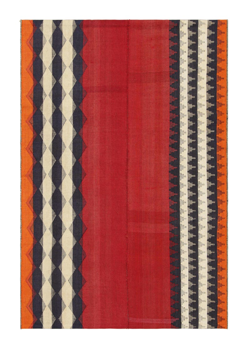 May include: A rectangular rug with a central red field and patterned borders. One border features a diamond design in navy, cream, and black, while the other has a repeating geometric pattern in white, black, and gray. Orange accents frame the edges.