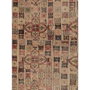 Op de afbeelding: Rechthoekig beige tapijt met een herhalend patroon van geometrische vormen in rood, zwart en crème. Het tapijt heeft een versleten, vintage uitstraling, geschikt voor woon- of slaapkamers.