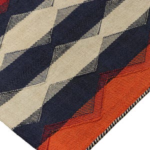 May include: Close-up of a woven rug with a geometric pattern. The rug features alternating diagonal stripes of navy blue, cream, and orange. The edges are finished with a black and white border. The rug is made of a textured material.