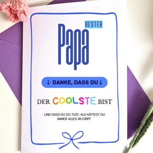 May include: A greeting card with the word "Papa" in large blue letters. The card has a blue border and text that reads "BESTER", "DANKE, DASS DU", and "DER COOLSTE BIST". A purple envelope and pink crocheted flowers are in the background.