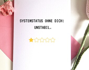 May include: A white greeting card with the text "SYSTEMSTATUS OHNE DICH: UNSTABIL." and a one-star rating. The card is on a pink envelope, with pink crocheted flowers in the background.