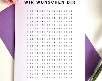 May include: A white greeting card with the text WIR WÜNSCHEN DIR above a grid of random letters and the text Die besten Wünsche sind manchmal gut versteckt. Finde alle 6 versteckten Wünsche. The card is placed on a purple envelope with pink crochet flowers.