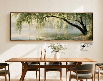 May include: A rectangular landscape painting featuring a weeping willow tree with green foliage hanging over a calm lake. The artwork is displayed in a wooden frame above a long wooden dining table with four chairs and a white vase with greenery.