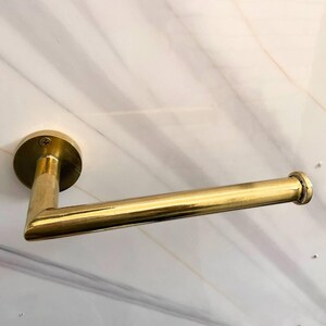 Peut inclure: Un porte-papier toilette de couleur or. Il est composé d'une base circulaire fixée au mur et d'une barre horizontale pour maintenir le rouleau. La finition est brillante et réfléchissante. Le design est simple et élégant.