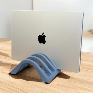 May include: A blue laptop stand made of plastic with two arches. The stand is holding up a silver laptop with an Apple logo.