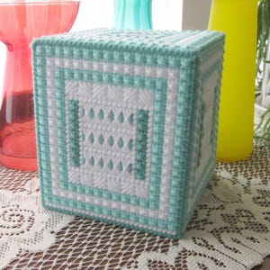 May include: A light blue and white crocheted tissue box cover with a geometric pattern.