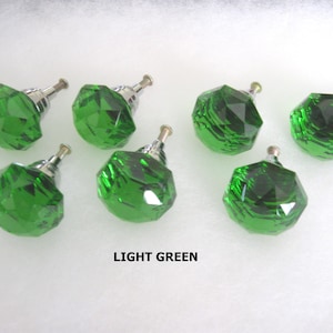May include: Seven light green faceted glass cabinet knobs with silver-toned metal hardware. The knobs are arranged on a white surface. The text "LIGHT GREEN" is below the knobs.