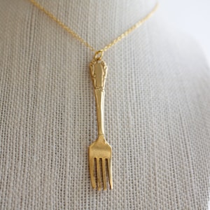 May include: A gold-tone necklace with a vintage fork pendant.
