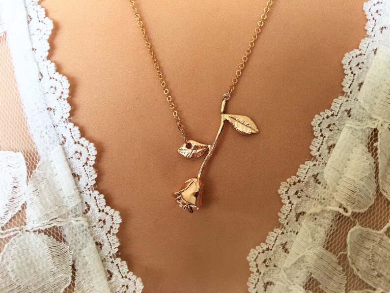 May include: A gold rose necklace with a delicate chain and a simple rose pendant.