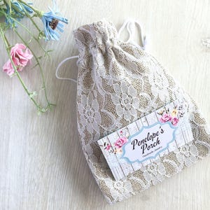 May include: A white lace drawstring bag with a tag that says "Penelope's Porch Handmade Jewelry".