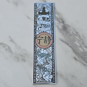 May include: A rectangular bookmark with a light blue background and black and white illustrations. The bookmark features the text "I am a Leaf on the wind" and Chinese characters. Decorative elements include a stylized ship and wave patterns.