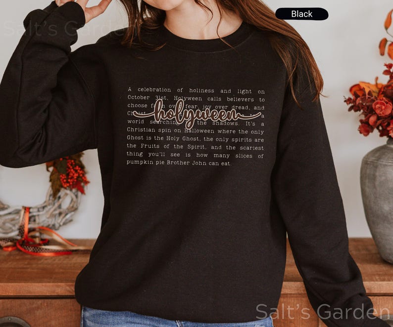 K&ouml;nnte beinhalten: Schwarzes Sweatshirt mit Rundhalsausschnitt und dem Wort "holyween" in Schreibschrift. Das Sweatshirt enth&auml;lt auch ein Gedicht &uuml;ber Holyween. Ein bequemer, l&auml;ssiger Stil.