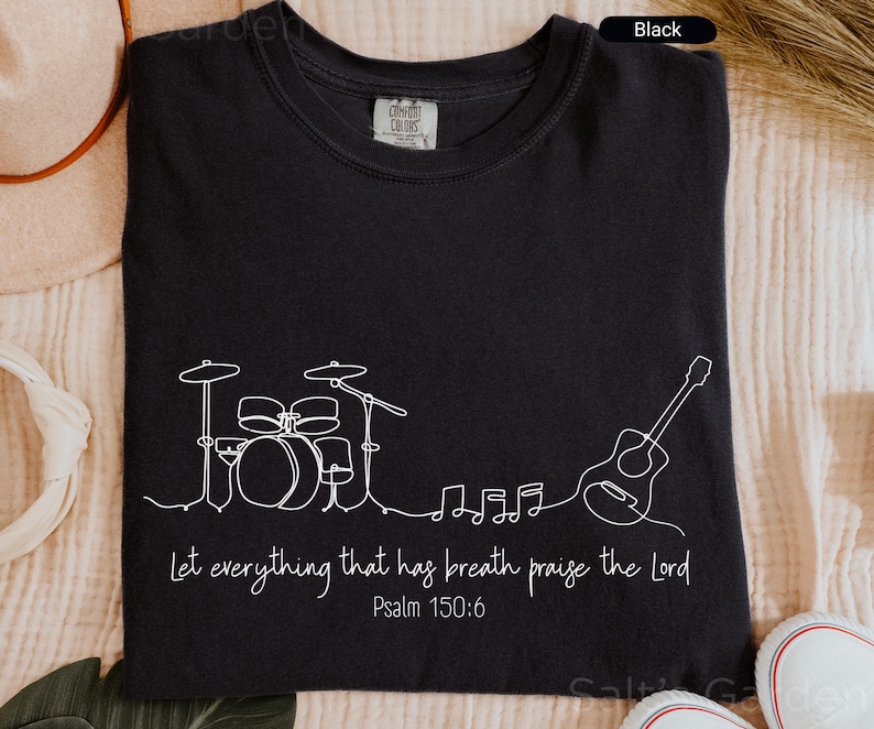 May include: Black t-shirt with a white line drawing of a drum set, guitar, and musical notes. The text "Let everything that has breath praise the Lord" and "Psalm 150:6" are also printed on the shirt.