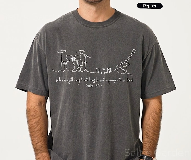 May include: Pepper-colored t-shirt with a white line drawing of a drum set, guitar, and musical notes. The text "Let everything that has breath praise the Lord Psalm 150:6" is printed below the musical instruments.
