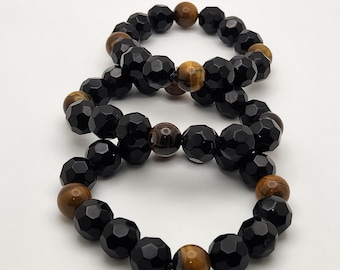 May include: Two beaded bracelets. Each bracelet features faceted black beads and round, brown tiger eye beads. The bracelets are displayed on a white surface. The beads are strung together to form a circular shape.