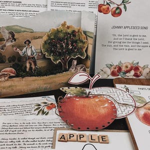 Könnte beinhalten: Lernmaterialien über Johnny Appleseed mit gedruckten Texten, Illustrationen von Äpfeln, einem Hasen und einer Person, dazu Holzbuchstaben, die APPLE bilden, und ein großer roter Apfel-Ausschnitt mit Stiel und Blatt auf weißem Untergrund.
