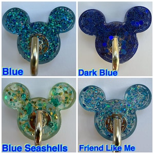 May include: Four resin wall hooks shaped like mouse heads, each featuring a metal hook. The designs include blue glitter, dark blue glitter, blue seashells with gold stars, and blue iridescent shards labeled Blue, Dark Blue, Blue Seashells, and Friend Like Me.
