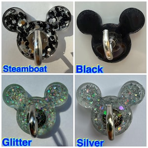 May include: Four mouse-shaped wall hooks with metal hardware. The Steamboat hook features black and silver glitter. The Black hook is solid black. The Glitter hook contains multi-colored iridescent sparkles. The Silver hook has silver glitter.