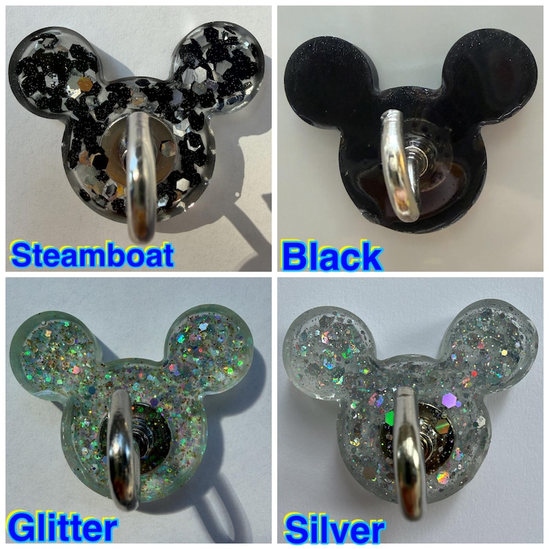 May include: Four mouse-shaped wall hooks with metal hardware. The Steamboat hook features black and silver glitter. The Black hook is solid black. The Glitter hook contains multi-colored iridescent sparkles. The Silver hook has silver glitter.
