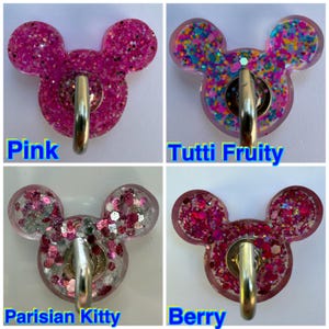 May include: Four mouse-shaped wall hooks with metallic silver hardware. The top left is pink glitter, top right is multi-colored confetti, bottom left is pink and silver glitter, and bottom right is dark pink and red chunky glitter.