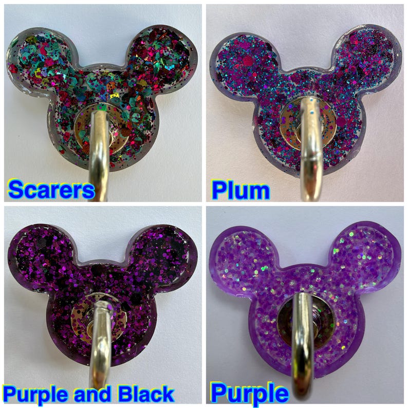 May include: Four resin badge reels shaped like mouse heads, each featuring a metal clip. The top left is labeled Scarers with multi-colored glitter, top right is Plum with purple and blue glitter, bottom left is Purple and Black, and bottom right is Purple.