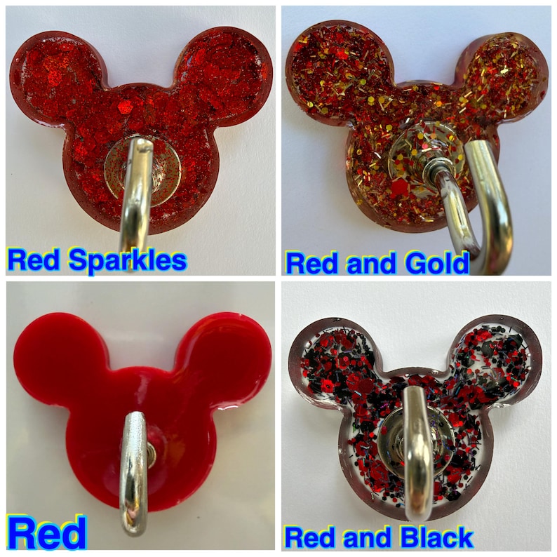 May include: Four Mickey Mouse-shaped wall hooks with metal hardware. One is solid red, one has red sparkles, one has red and gold glitter, and one has red and black glitter. Text labels read Red Sparkles, Red and Gold, Red, and Red and Black.