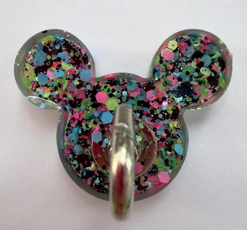 May include: A clear resin wall hook shaped like a mouse head, filled with a dense mix of multicolored hexagonal and fine glitter in shades of neon pink, bright blue, lime green, and black, featuring a central silver-toned metal hook.