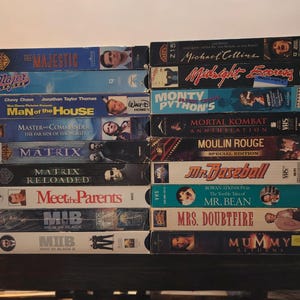 Può includere: Una pila di cassette VHS con film popolari come The Majestic, Major League, Man of the House, Master and Commander, The Matrix, Meet the Parents, MIB, Mrs. Doubtfire e The Mummy Returns.