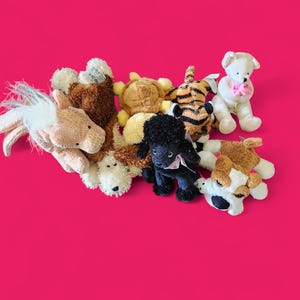 May include: A group of seven plush toys, including a brown and white horse, a brown turtle, a brown and orange tiger, a black dog, a brown and white dog, a white dog with pink ears, and a brown and white dog with a pink bow.