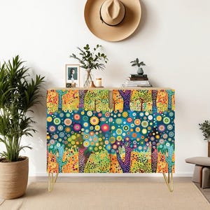 May include: A colorful cabinet with a whimsical forest design. The cabinet features a vibrant pattern of trees, flowers, and dots in shades of blue, green, orange, and yellow. It has gold hairpin legs and is set against a neutral background.