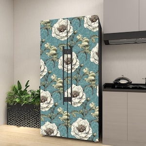May include: A refrigerator with a floral design. The doors are covered in a teal background with large white and brown flowers and green leaves. The refrigerator is in a kitchen setting.