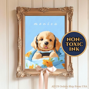 Könnte beinhalten: Gerahmter Druck mit einem Golden Retriever-Welpen, der Kopfhörer trägt und einen Gamecontroller hält. Der Welpe liegt in einer blauen Decke mit orangefarbenen Blumenmustern. Das Wort "monica" steht darüber. Der Rahmen ist verziert und goldfarben.