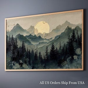 May include: Textured landscape painting with a golden sun over a mountain range and a forest of dark green trees. The artwork is framed in a light wood frame, creating a serene and natural aesthetic.