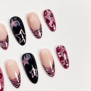 Puede incluir: Un conjunto de u&ntilde;as postizas con varios dise&ntilde;os. Algunas u&ntilde;as son negras con dise&ntilde;os de estrellas brillantes, otras son nude con rayas de cebra brillantes y otras son rosas con estampado de leopardo.