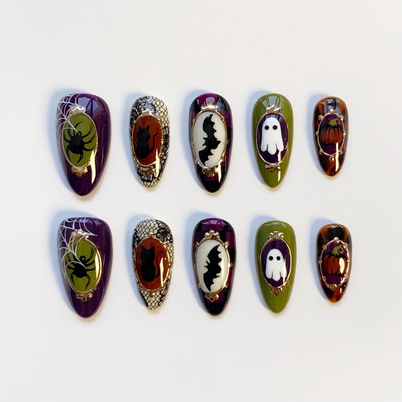 May include: A set of ten Halloween-themed press-on nails. Each nail features a different design, including a spider and web, a black cat, a bat, a ghost, and a pumpkin. The nails are oval-shaped and painted in various colors, including purple, green, and orange.