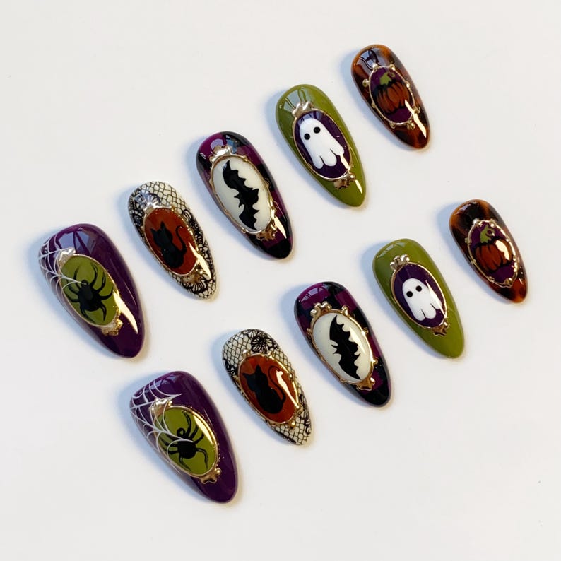 May include: A collection of Halloween-themed false nails. Designs include a spider web with a spider, a bat, a ghost, and a pumpkin. The nails feature a variety of colors, including purple, green, orange, and black, with gold accents.